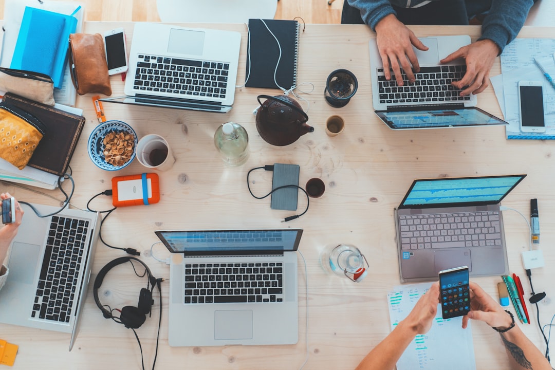 creative people-sitting-down-near-table-with-assorted-laptop-computers-syto3xs06fu